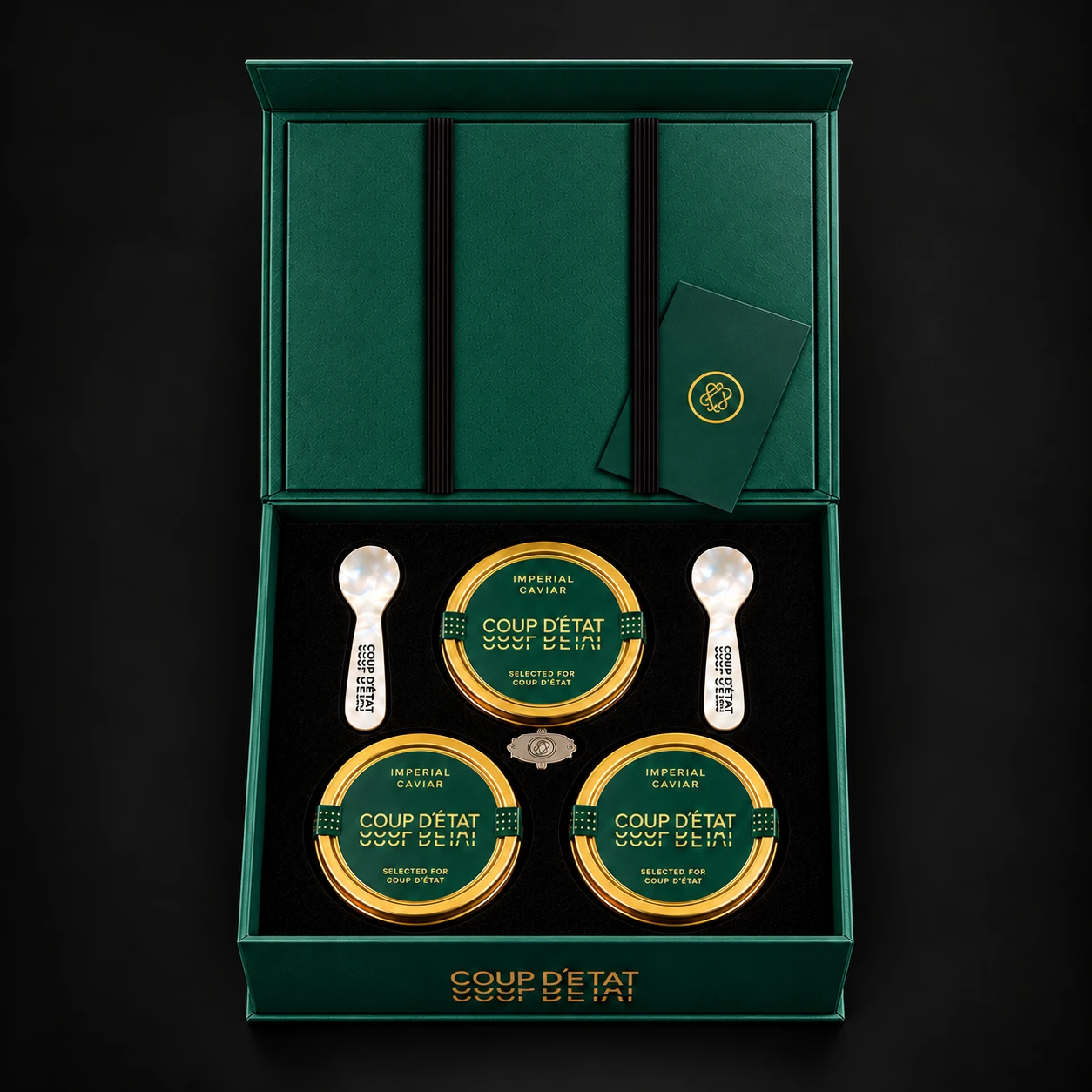Overhead view of the forest-green Coup d’État caviar gift box with three gold tins and mother-of-pearl spoons
