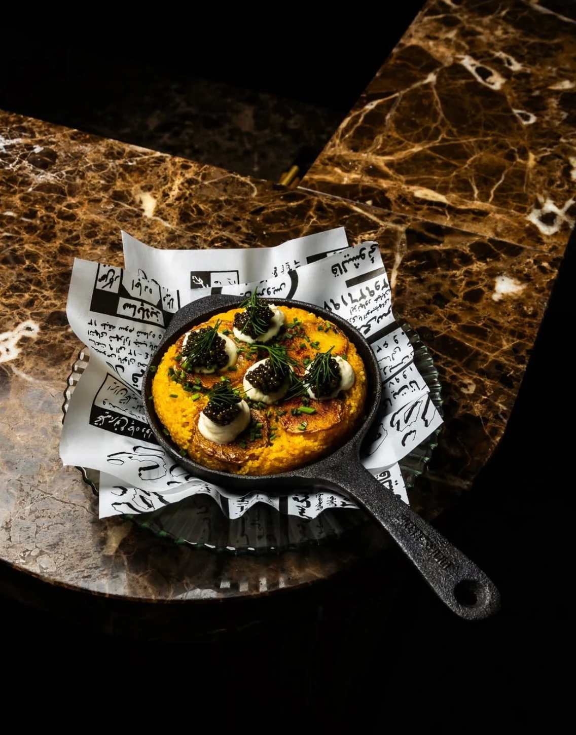 Tahdig topped with caviar in a cast-iron pan
